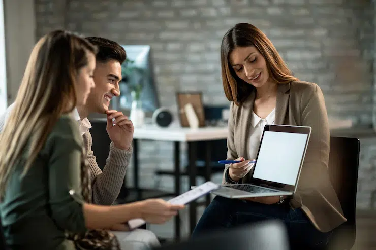three people making  using computer while having meeting with young couple making busness plans